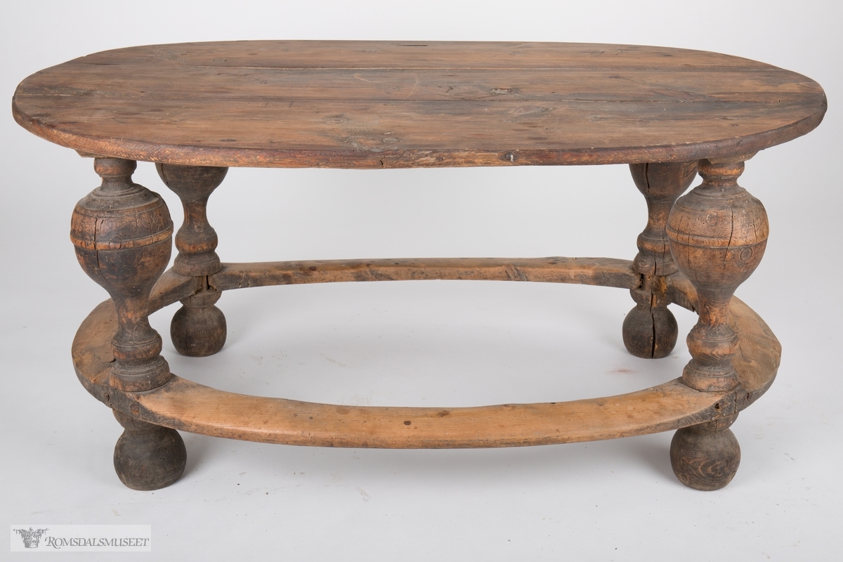 Ovalt trebord med balusterformede ben som har en sammenbindende sville som går rundt hele bordet. Rester etter brun maling.