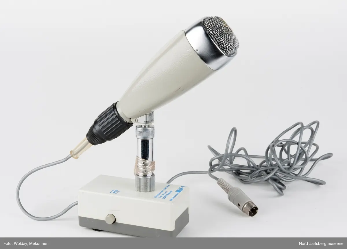 Bordmikrofon montert på en kort stang til en rektangulær fot (forsterker?)med to forskjellige el-kobling til headset?
Selve mikrofonen er kantet konisk med lydhode i blan
kt metall.