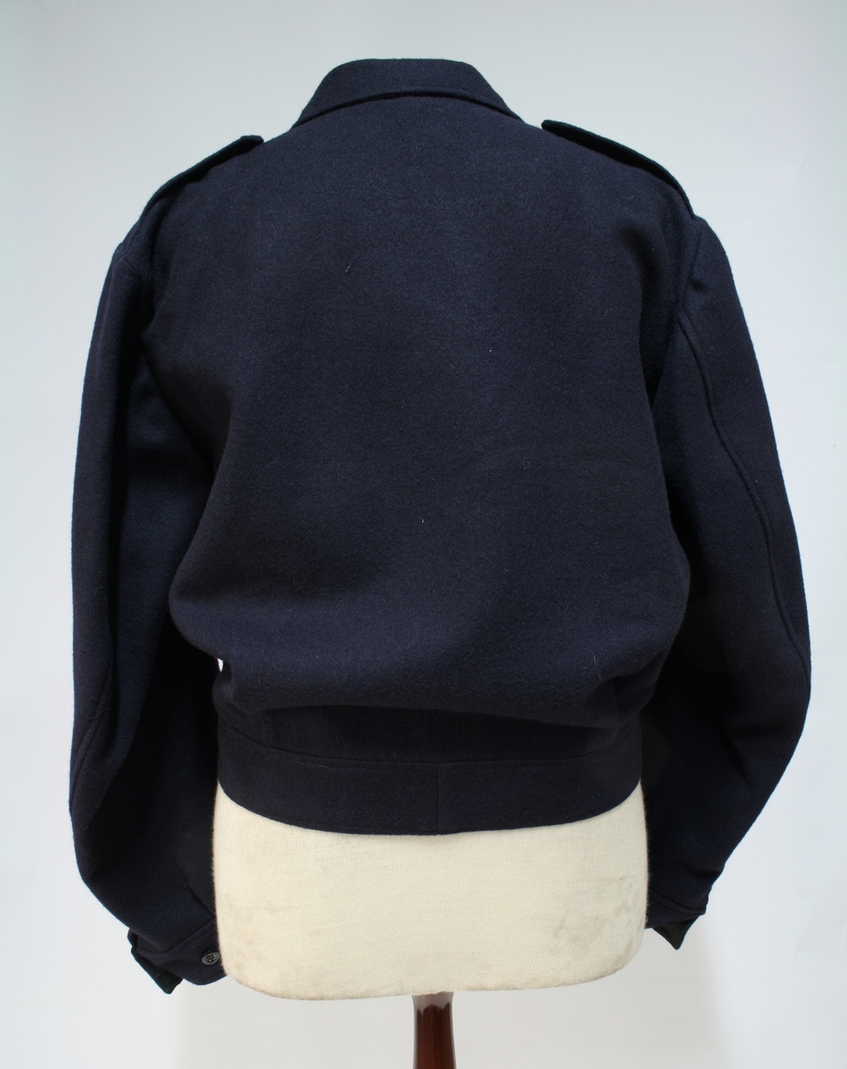 Mørkeblå gylfknappet jakke med innstramming i linningen.