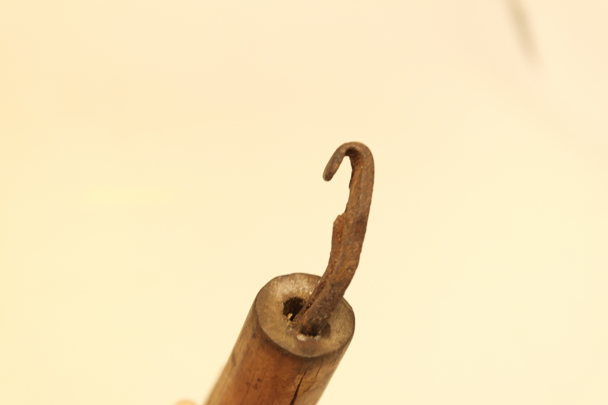 Merkejern bestående av håndtak i skåret og pusset furu, og en tange i smidd jern. Jernet er tappet inn i håndtaket, bøyd i vinkel, krumt ytterst, med en egg på en side.