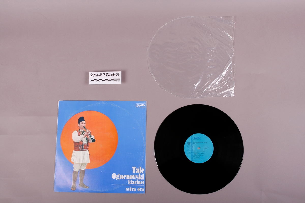 Grammofonplate i svart vinyl og plateomslag i papp. Plata ligger i en plastlomme. Tekst er skrevet på baksiden av omslaget, med blå penn. Se bilder.