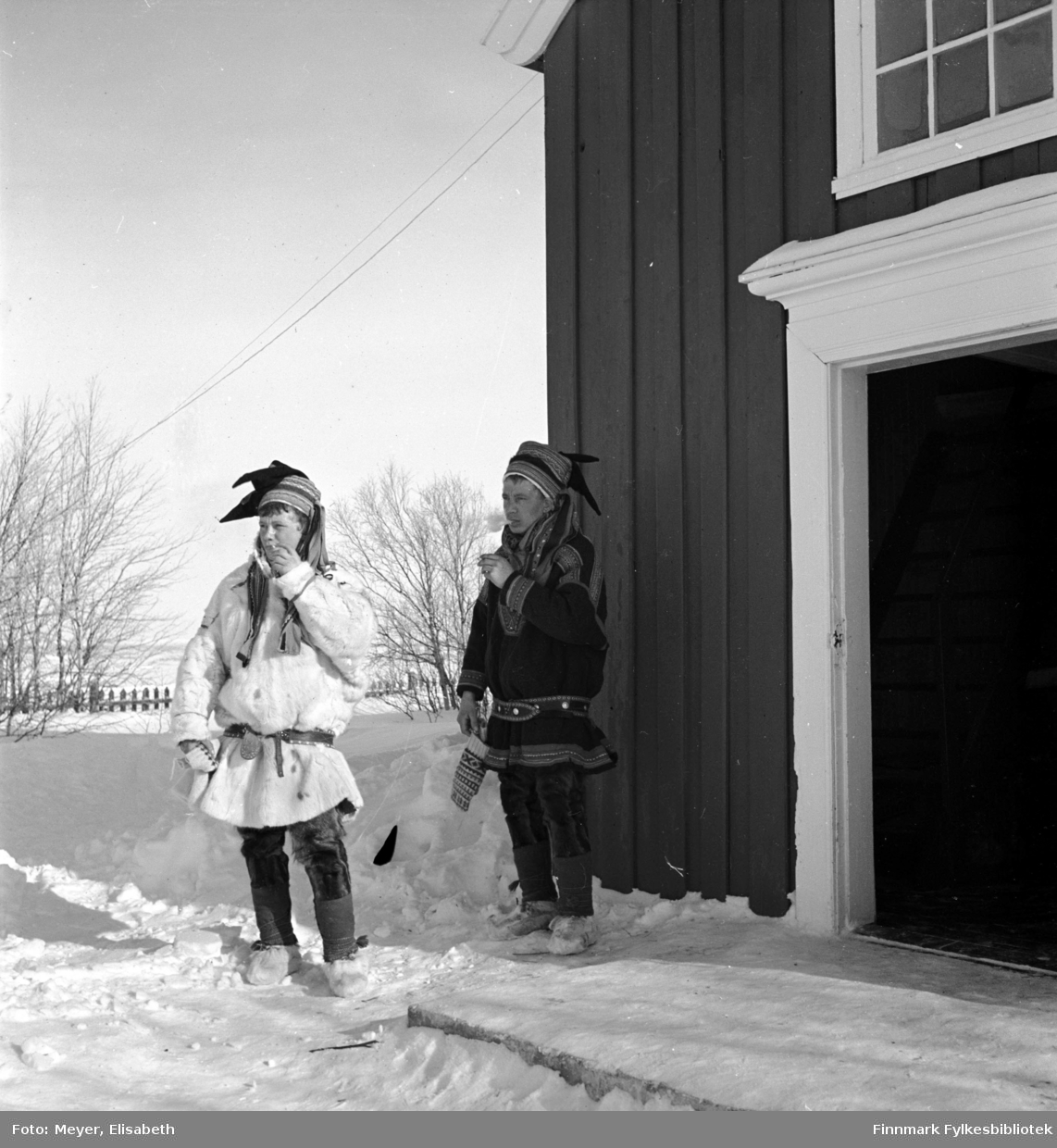 Røyekpause utenfor Kautokeino kirke. To unge samiske gutter i sin fineste stas. Navn ukjent.