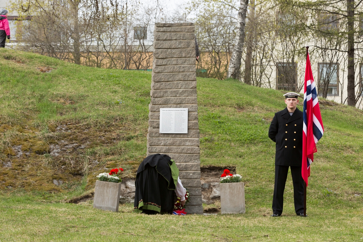 Ordfører Marianne Bremnes legger ned blomster ved avduket minnesmerke. Til høyre står marinegast med flagg.