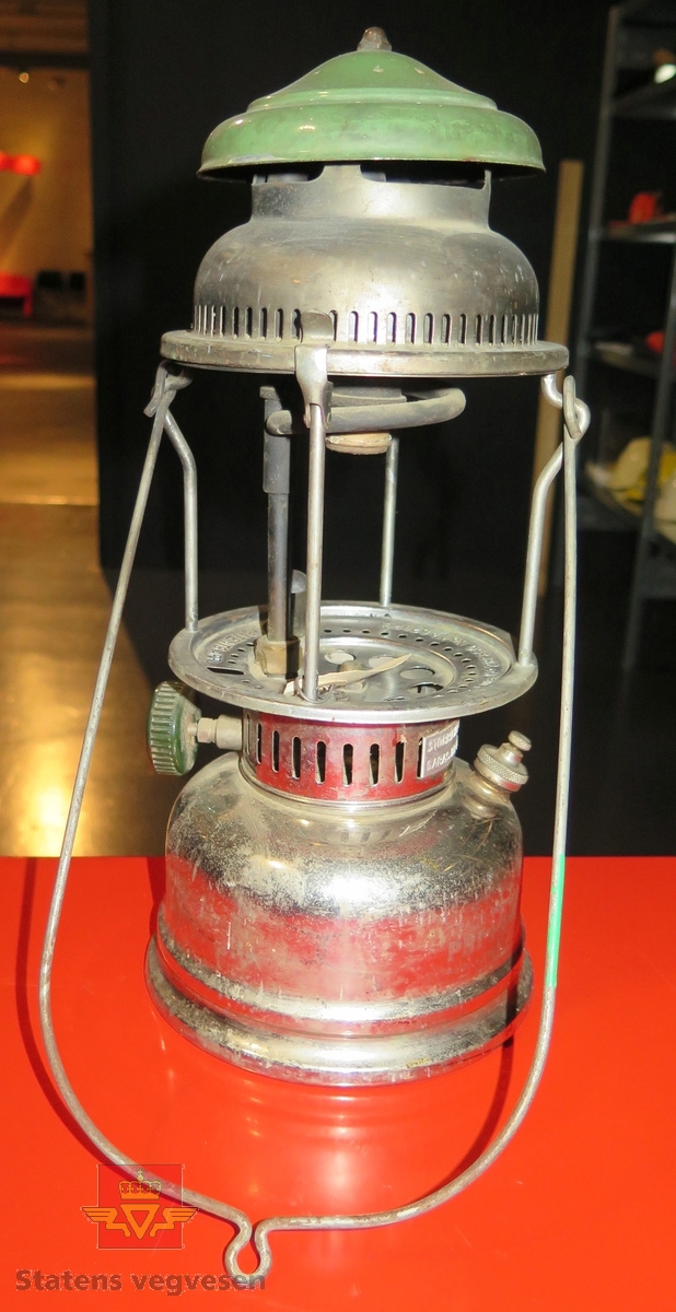 Parafinlampe. Lagd av metall og glass. Kan bæres. Med denne pumper du opp trykket på parafin før bruk.