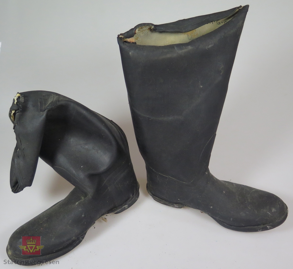 Ett par svarte gummistøvler. Slitte og delvis defekte.