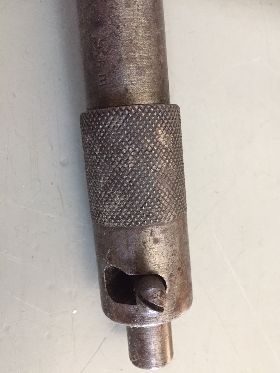 I nederkant kjegleformet sylinder, som smalner inn mot en stålsylinder med utløsermekanisme. 