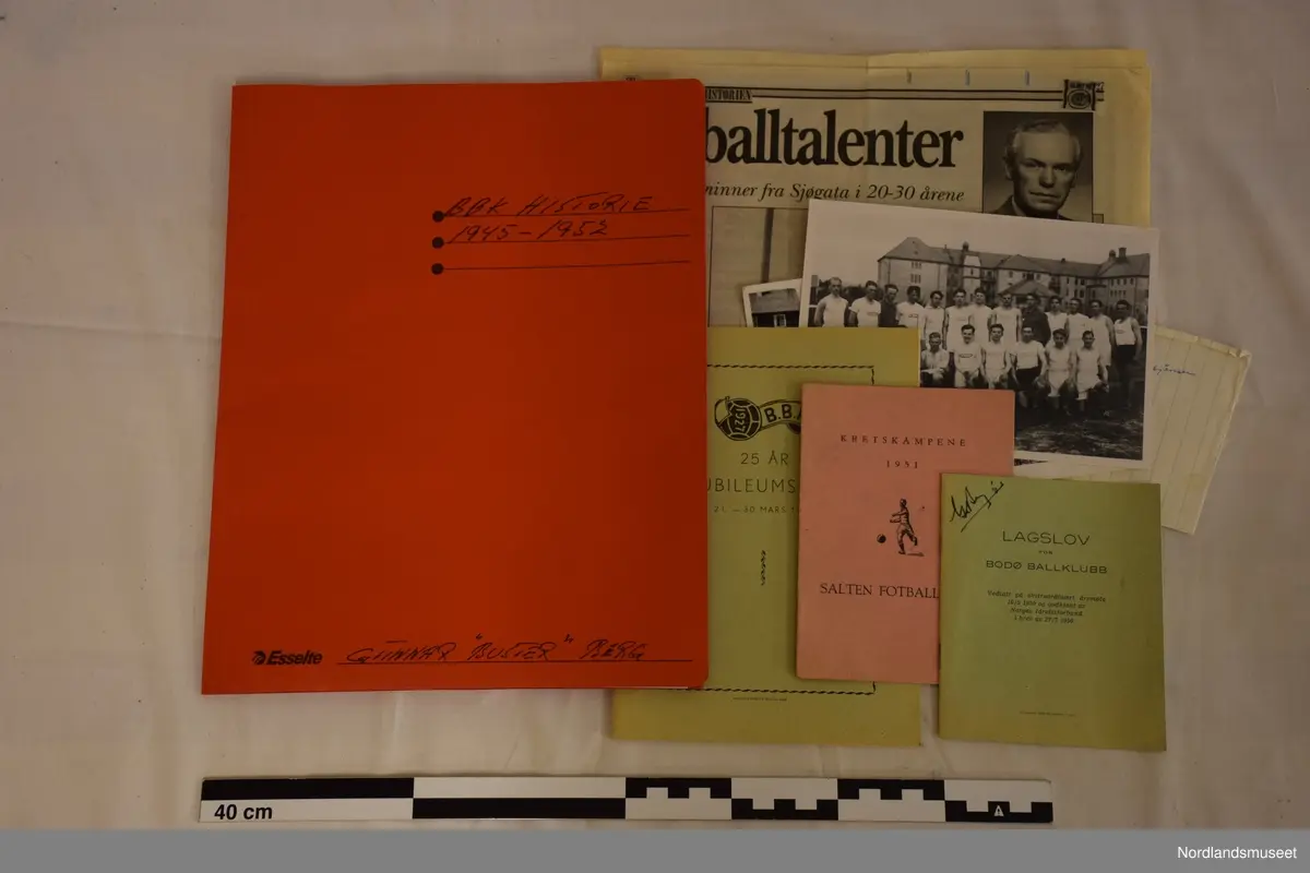 Ni sølv pokaler, en stor grønn banne, to blå liten trekantet flagge, to  runde keramik og diverse tekster om klubben.