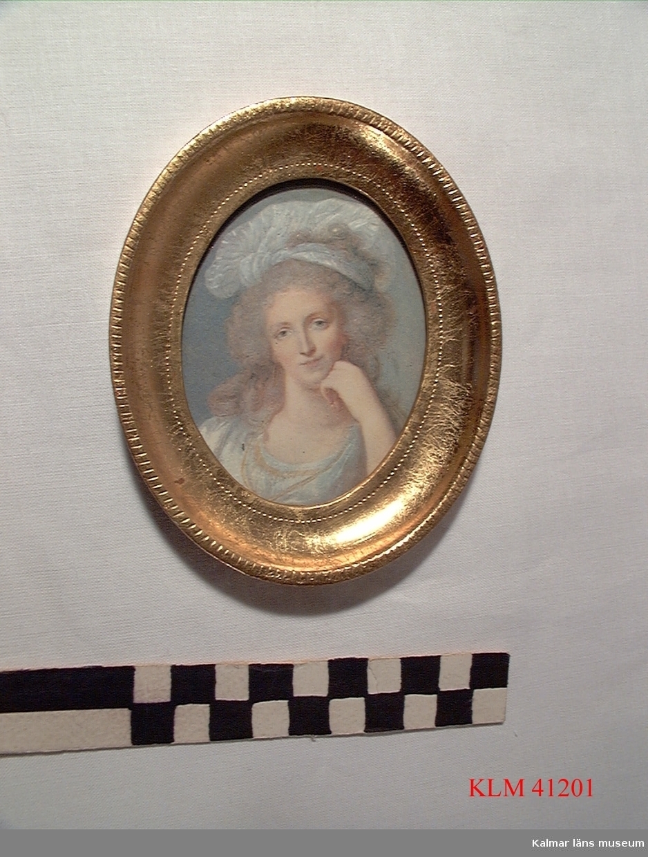 KLM 41201 Tavla, tryck på papper. Stående oval, i förgylld träram. Kvinnoporträtt, klädd i 1700-talskläder.