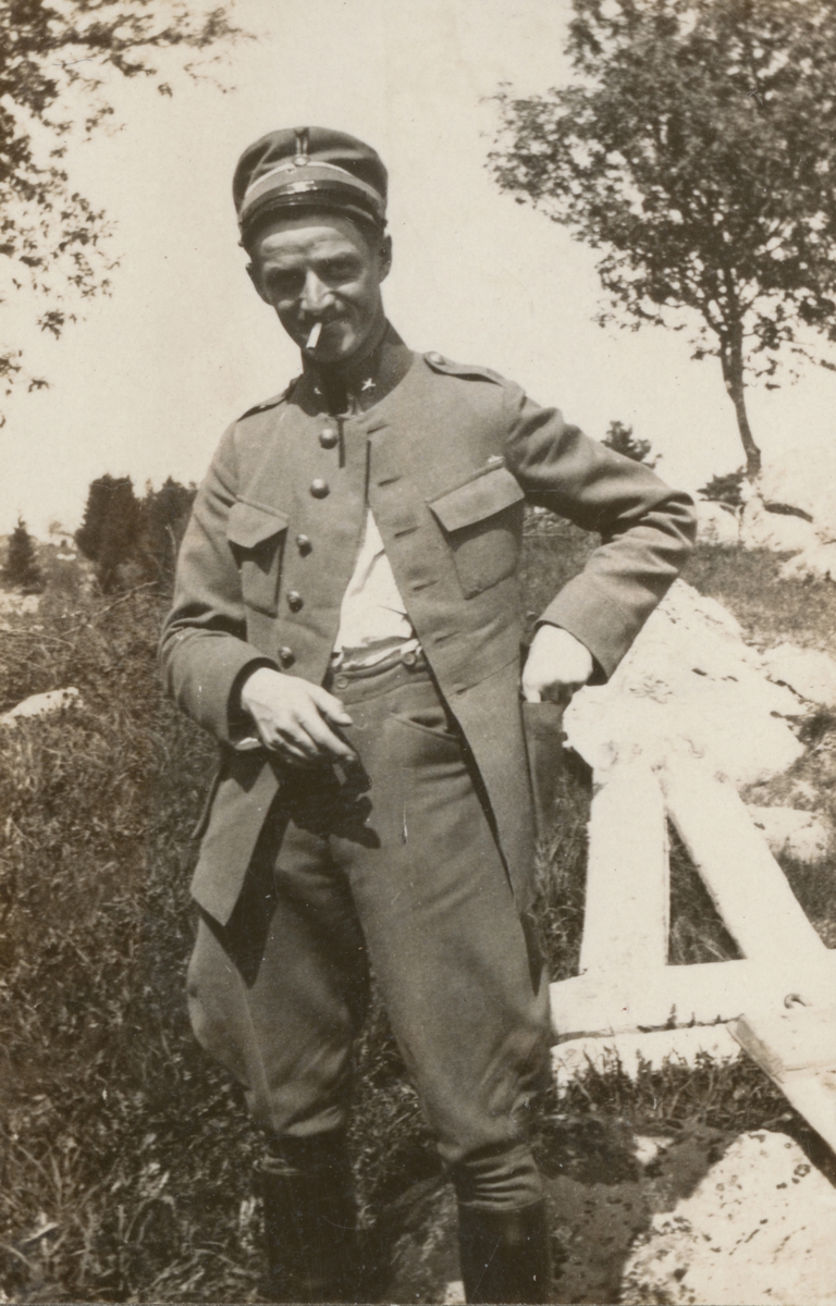 En soldat från Södermanlands regemente med uppknäppt jacka och cigarett i munnen på en kulle.