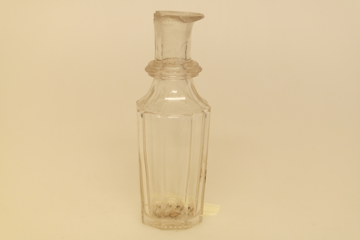 Kryddersett bestående av stativ (a), to flasker (b, c, f) og to glass (d-e).
A) Krydderstativ av tre og støpt messing. Messingkant rundt 4 sirkelåpninger. Fire balusterformede messingbein.
B) Flaske i støpt glass med glasspropp (F)
C) Flaske i støpt glass
D) Støpt glass