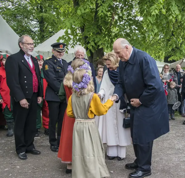 Kongeparet tas imot av blomsterpiker i middelalderkjoler, med blomsterkranser på hodet.