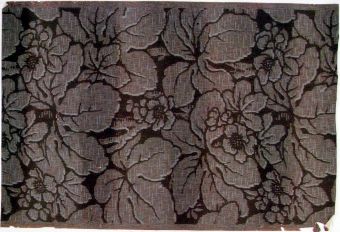 Stort sgrafferat blom-/bladmönster i grått och rosa på en brunbeige bakgrund.