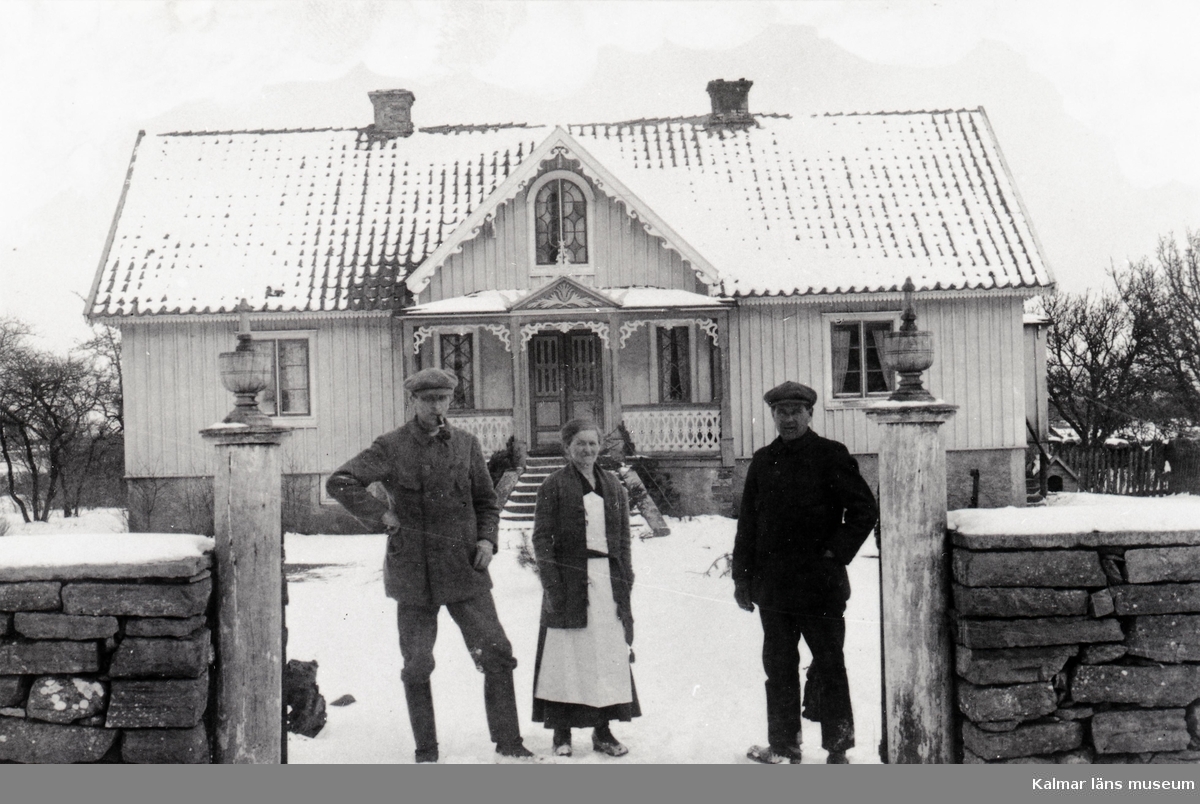 John Petersson och hustrun Elna framför mangårdsbyggnaden på sin gård. Personen till höger okänd. Troligen är det drängen på gården.