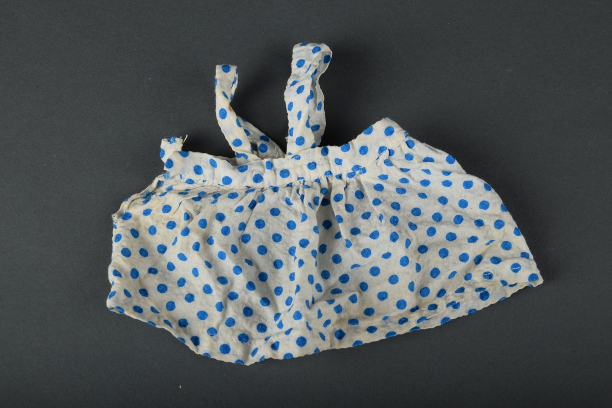 Dukkekjole utformet som et skjørt med seler. Hvitt med blå polkadotter.