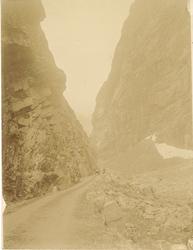 amatørfotografi av vegparti mellom bratte fjell med steinur 