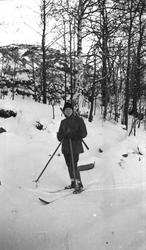 Vinter og snø. En kvinne ute på skitur med hagle på ryggen. 