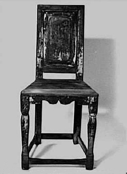 Brunmålad stol med hel, spegelförsedd ryggbricka. Spegeln har spår av dekor i rött och blått. Profilsågade framben. På framsargen 2 utsågade bågar. Lågt sittande tvärslåar.



Neg.nr: 981/1047:9