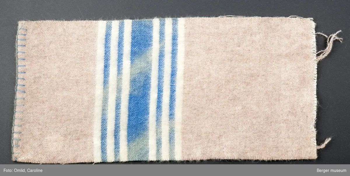 En prøve. Ensfarget gammelrosa med en bred blå stripe med to smalere striper på begge sider av den brede og hvite offwhite striper i mellom og utenfor de blå.