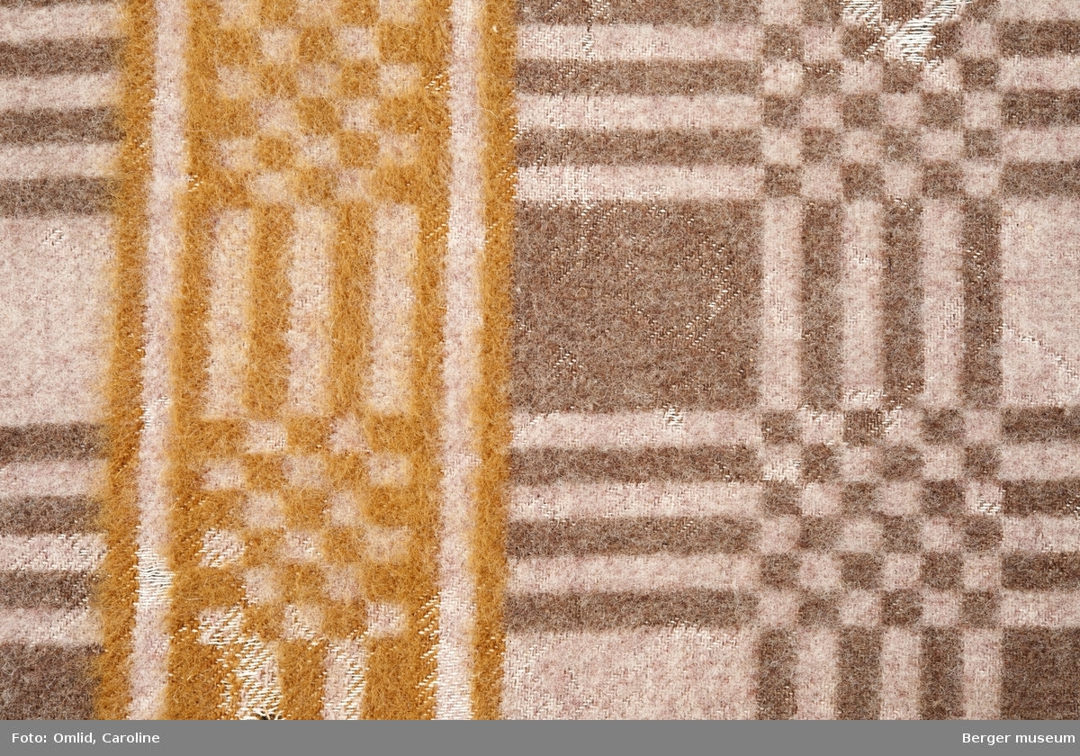 Teppe med geometrisk rutemønster i brune nyanser. En tverrgående bord med samme mønster, men i en rødbrun farge.