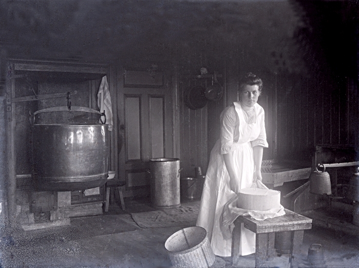 Interiör från mejeriet där Emilia lägger en duk omkring osten.
Emilia senare gift med Teodor Karlsson, Kvarnbolet, Töreboda.