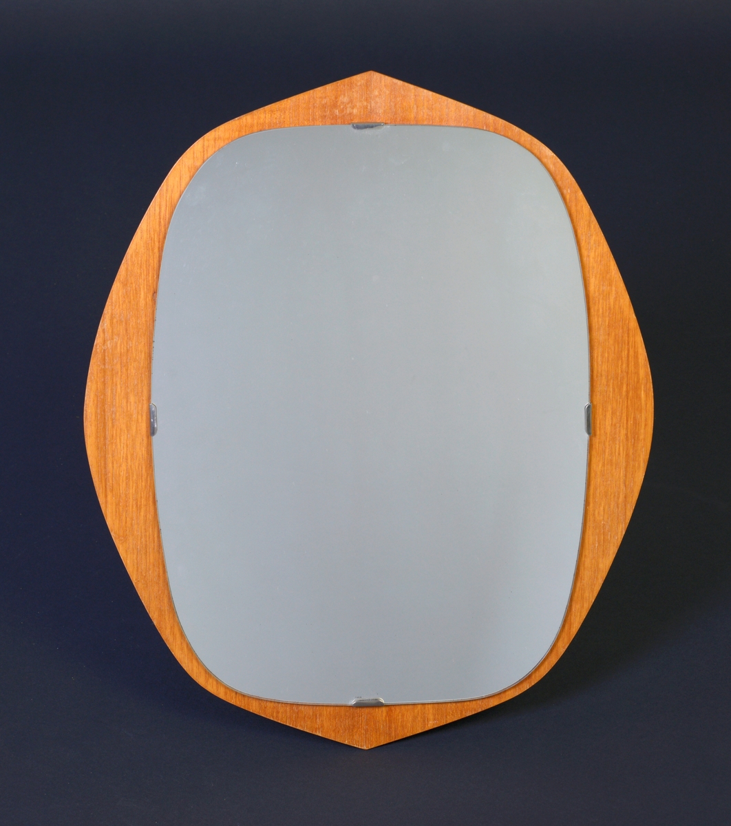 Rundt-ovalt speil laget av kryssfiner og speilglass. Rammen er laget av kryssfiner og er rundt til ovalt med en lien spiss i begge ender. Speilglasset er firkantet med avrundede hjørner. Speilet er festet til rammen med metallklips. På baksiden er det festet en trekantet metallhempe for oppheng.