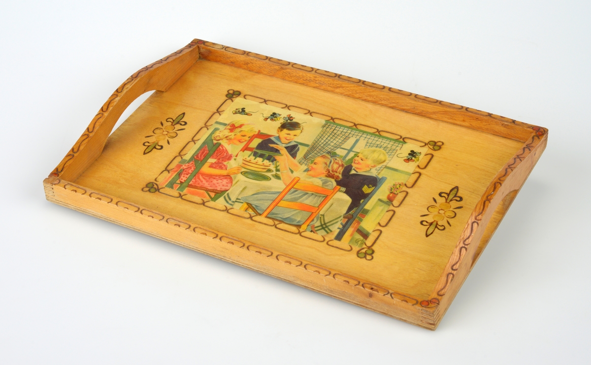 Et firkantet serveringsbrett laget av kryssfiner og tre. Flaten er kryssfiner og på midten er det limt på et trykk (papir) som er lakkert. Motivet er to jenter i kjole og to gutter i matrosdress som sitter ved et bord. På bordet er det kake. På veggen i rommet de sitter i er det små figurer som er Mikke Mus og Minnie Mus (den eldre versjonen av figurene). Rundt bildet er det en bord gjort ved svidekor. På hver side av bildet er det en bloms som er malt og svidd. Det er en kant av tre rundt hele brettet. I siden er denne kanten noe høyere og buet. Det er også skåret ut slik at det er håndtak i hver side. På kanetn er det svidekor, og i hvert hjørne er det malt i svidekoren (røde rundinger).