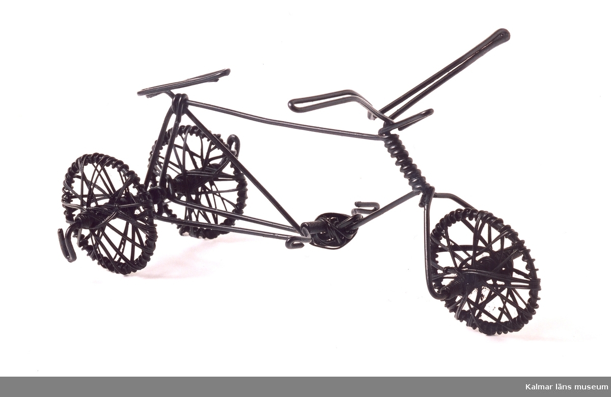 KLM 39586:56. Cykel, trehjuling, av ståltråd, svartmålad. Trådarbete. Tillverkad av Erik Andersson kallad Öland eller Lille Öland.