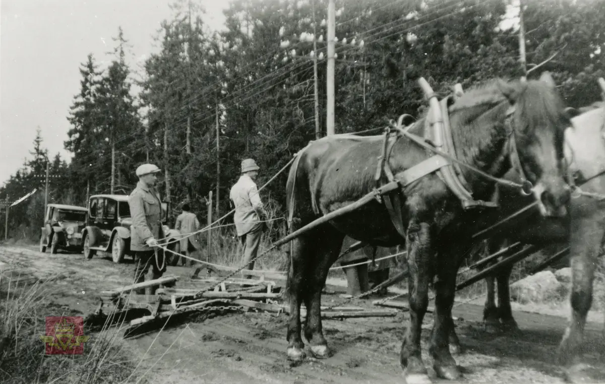 Amerikansk veghøvel "Russel Grader"  i arbeid i Østfold 1924, i følge merking.  Ref. til "Meddelelser fra Veidirektøren", Nr. 47-mai 1924. Artikkel om "Prøve med den amerikanske veihøvel "Russel Grader" samt skrapning av veibanen med "Western" skrape", av overingeniør Thor Olsen. Befaring  med vegdirektoratets og Østfold fylkets ingeniører.  Andre bilder av veghøvelen som er illustrert i artikkelen vises i bildeframvisning 2/5 og 3/5. Bildeframvisning 4/5: "Skraperne av "Western"-typen forarbeides som nævnt ved fylkets verksted og utstyres nu med en fast arm paa den ene side for styring av hele redskapen foruten den bevægelige for stillingen av bladene , som det vil sees av fig. 5". Bildeframvisning 5/5: Vedlikeholdsarbeid med amerikansk vegskrape utføres i Østfold.