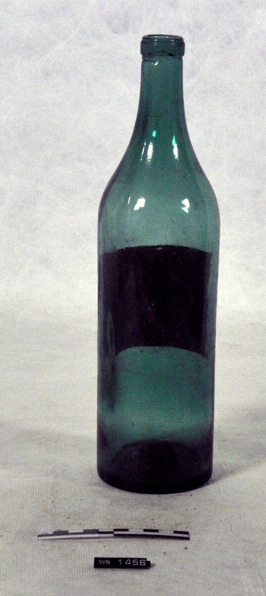 Grønn flaske uten kork.
Flasken har etikett.