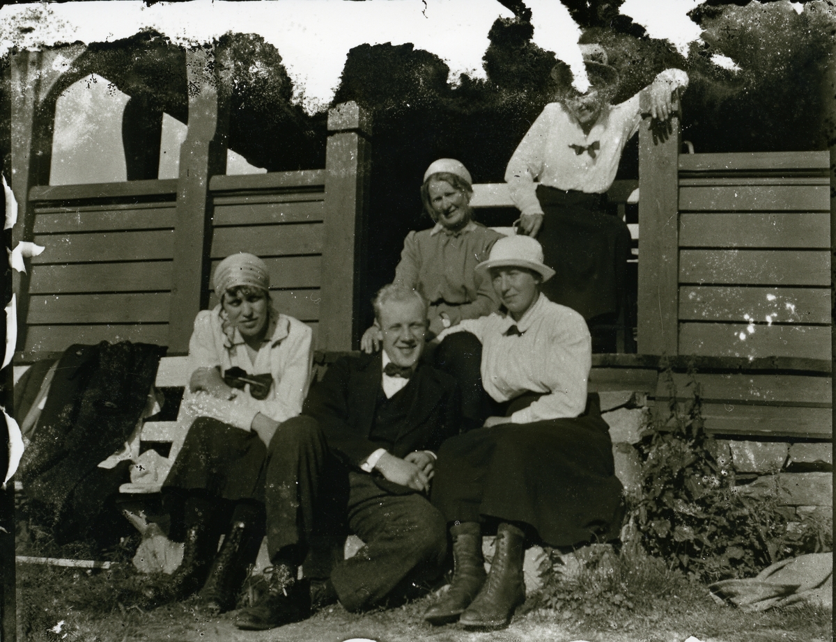 Fire kvinner og en mann sitter på ei trapp. Sannsynligvis Gausdal Høyfjellshotell.