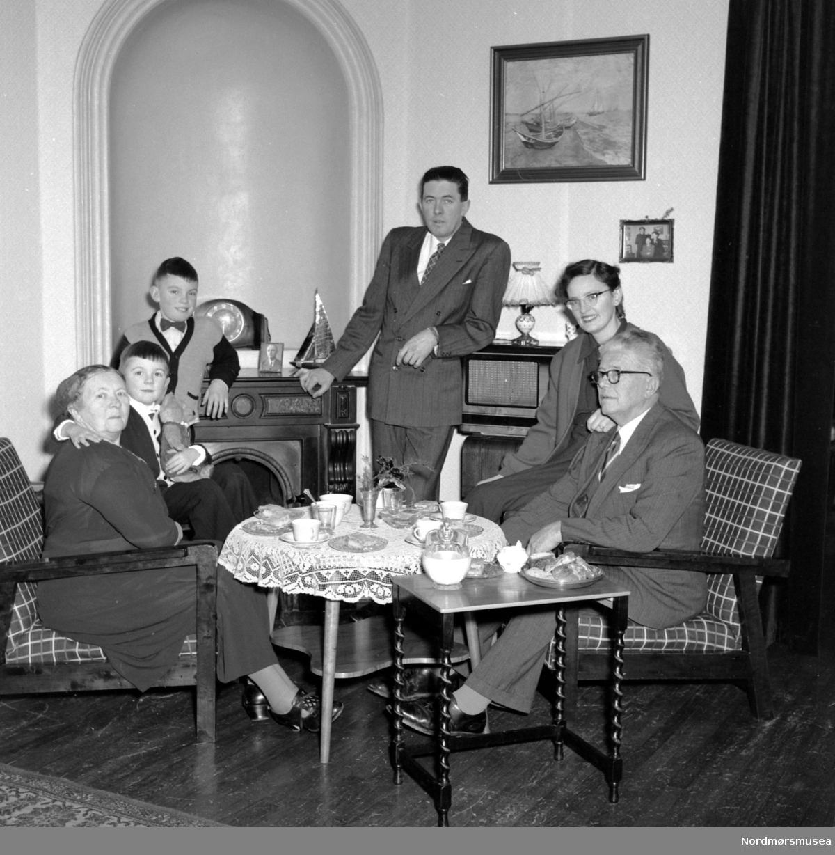 Familiefoto fra slekten Frislid i Kristiansund, hvor vi ser familien samlet rundt tebordet. Utover etternavnet, er det ukjent hvem vi ser på bildet, men mannen i midten er trolig Per Frislid. Fra Nordmøre museums fotosamlinger. EFR2015
