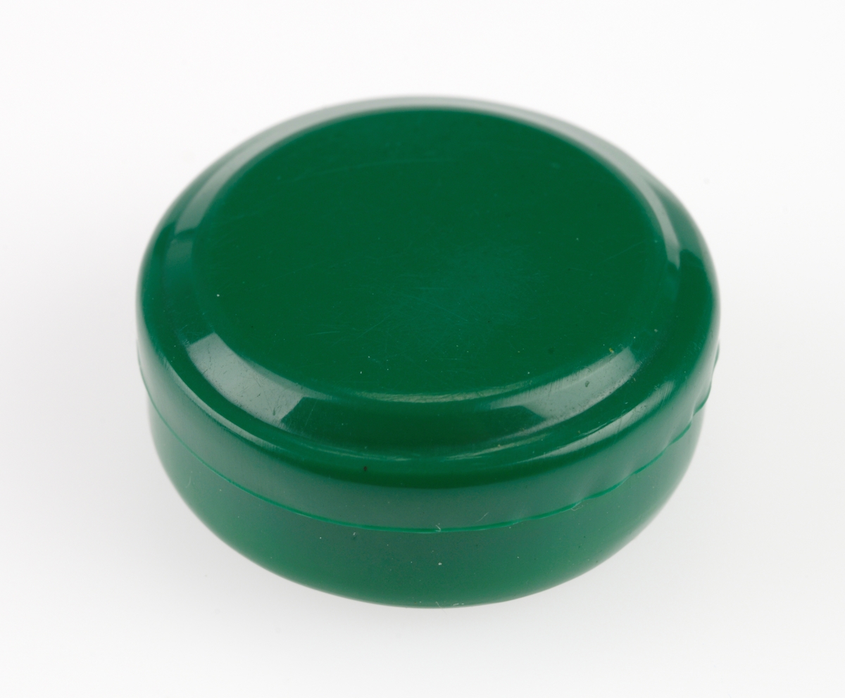 En rund liten eske laget av grønn plast. I boksen ligger det bomull og to ettøringer fra henholdsvis 1929 og 1937. Det er også en liten rød "edelstein" laget av plast i boksen. Ettøringene og "edelsteinen" er ikke merket med FTT-nummer.