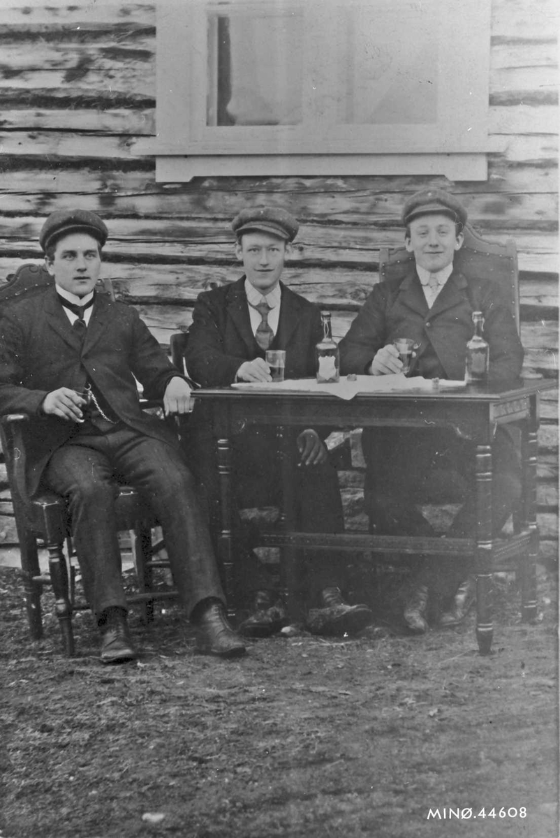 Tre dresskledde unge menn koser med en dram