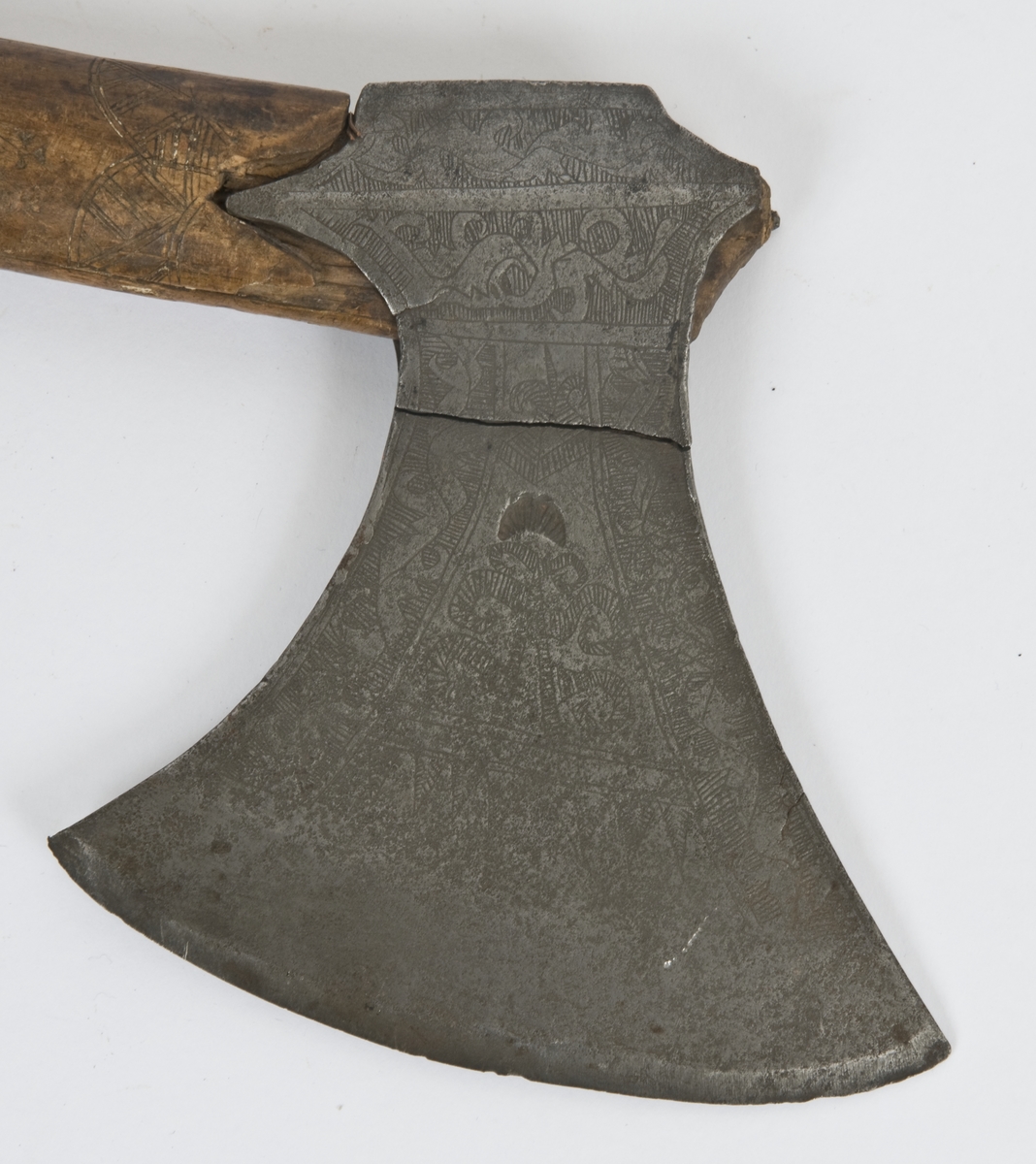 Asymmetrisk blad med lang øvre spiss og kortere nedre spiss.
Bladet er tynt, med påsmidd noe tykkere egg.
Øksehammeren har skaftehull og fliker.
Smedmerke formet som et skjell. Øksen har etset rankedekor på begge sider.
Skaftet er svakt krummet. Skaftet er merket på ryggen SON ANO 1700.Skaftet har skåret dekor i felter.