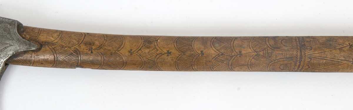 Asymmetrisk blad med lang øvre spiss og kortere nedre spiss.
Bladet er tynt, med påsmidd noe tykkere egg.
Øksehammeren har skaftehull og fliker.
Smedmerke formet som et skjell. Øksen har etset rankedekor på begge sider.
Skaftet er svakt krummet. Skaftet er merket på ryggen S 1683 .Skaftet har skåret dekor i felter. Skaftet har jernring nede.