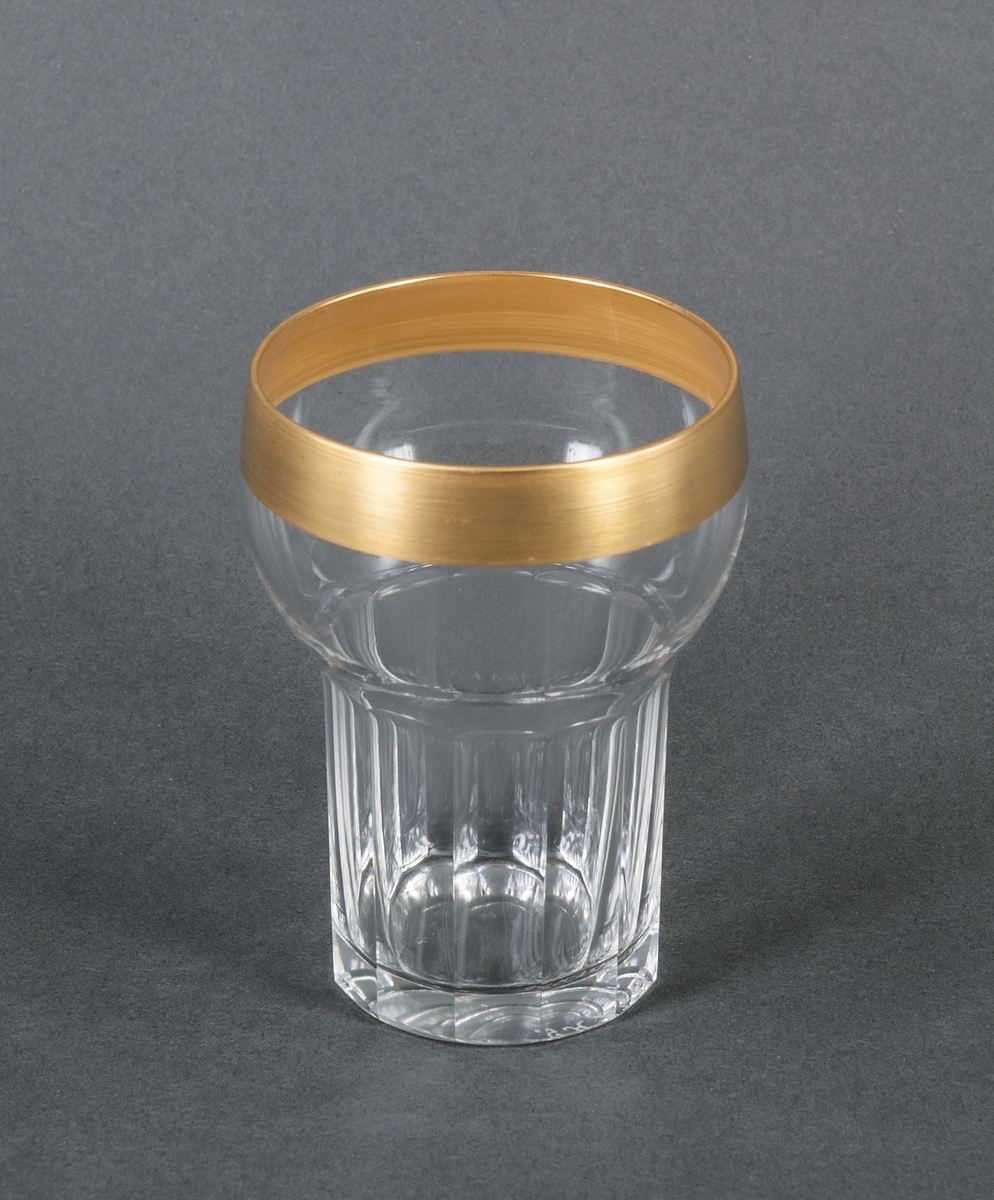 Selterglas i halvkristall. Servisglas. Sandviks glasbruk, design Gunnar Cyrén. Övre halvan konvex med bred guldkant, nedre halvan rak, smalare, med slipade facetter.