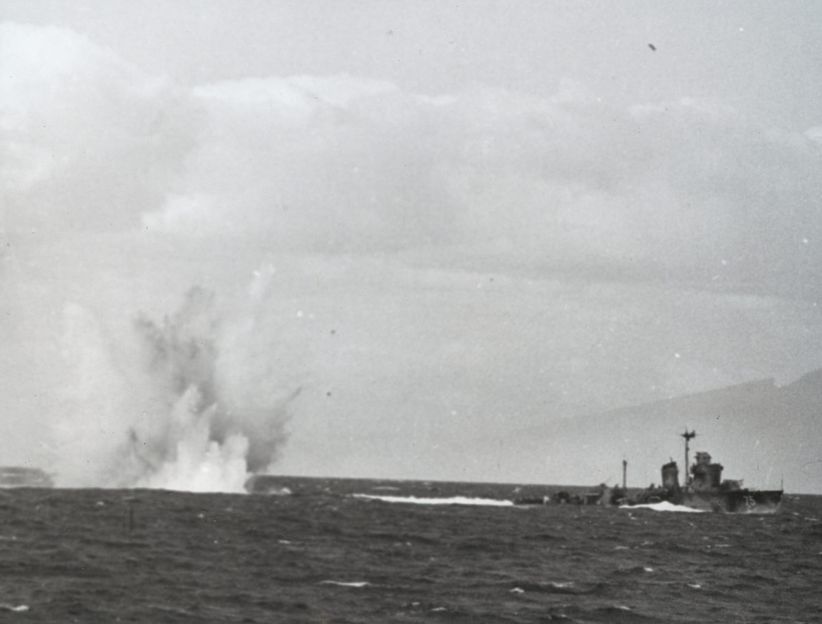 Kustjagaren HMS Munin (75) genomför en övningskjutning i Skälderviken, vilken orsakar att vattenmassor kastas upp. Bilden är tagen i samband med "Operation kullen" 1955.