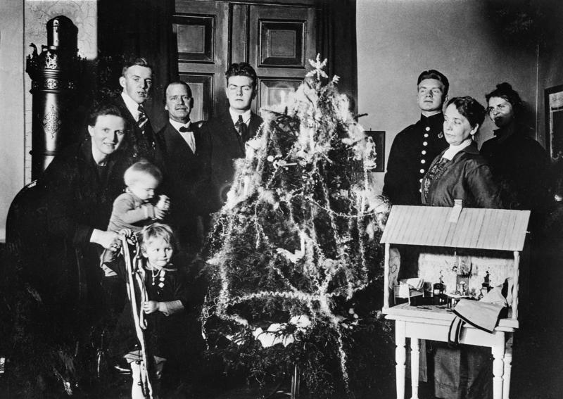 Svart-hvitt foto av familie som poserer ved juletreet i stua.