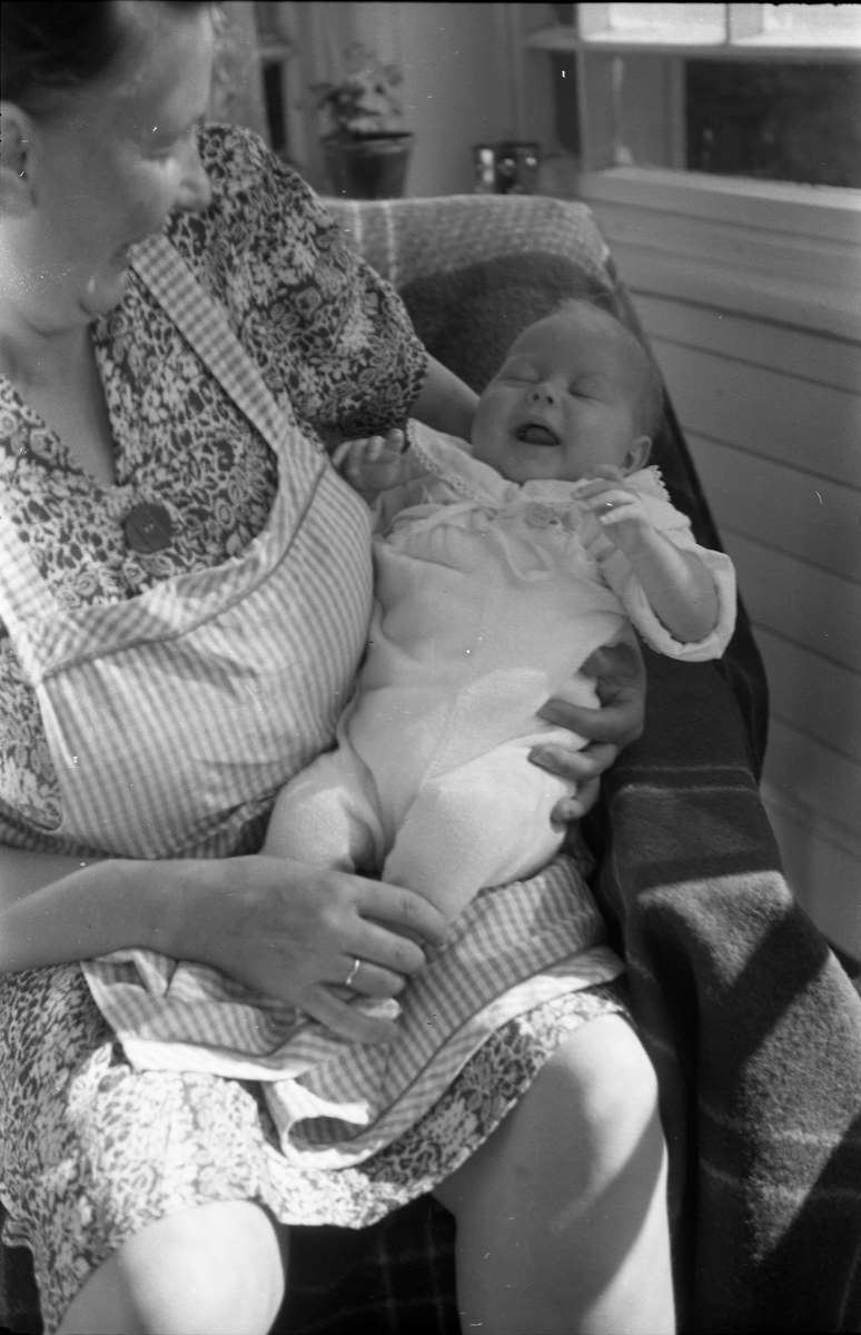 Uidentifisert lite barn. Serie på 10 Bilder. På noen av bildene holdes barnet av kvinner som bare delvis vises, og som heller ikke er identifisert.