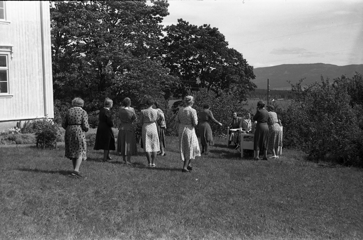 Fem bilder av en gruppe kvinner foran våningshuset og i hagen på gården Kraby østre i Østre Toten. Anledningen er muligens Borghild Nøklebys 60 års jubileum. På bilde nr. 1 står hun som nummer to fra høyre.