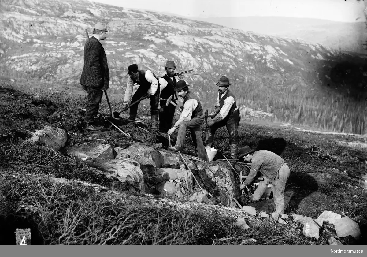 Foto av seks personer i et steinbrudd, trolig i Sunndal kommune. Fra Sunndal museumslags fotosamlinger.
