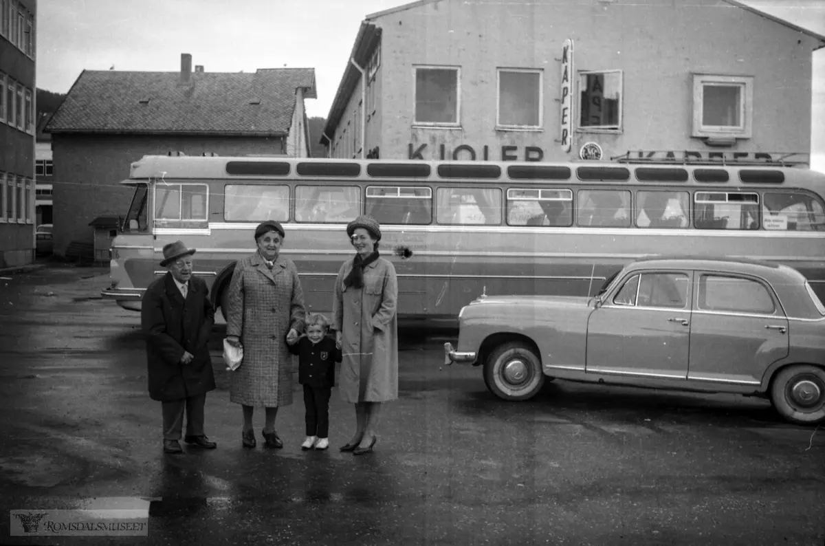 "Frå 21.08.1965"."Kongsli sitt besøk etc".Bussen i bakgrunnen tilhørte Veøy Billag. Den var registrert T-8595. Det var en DAF TB160, 1964-modell, med karosseri påbygd ved Arna Bruk. Den hadde 46 sitteplasser. Bussen gikk i mange år i ruter Molde-Åndalsnes, seinere i skoleruter. Etter at den var ferdig i rutetrafikk ble den solgt og ombygd til campingbuss. Den var registrert helt til 2006.