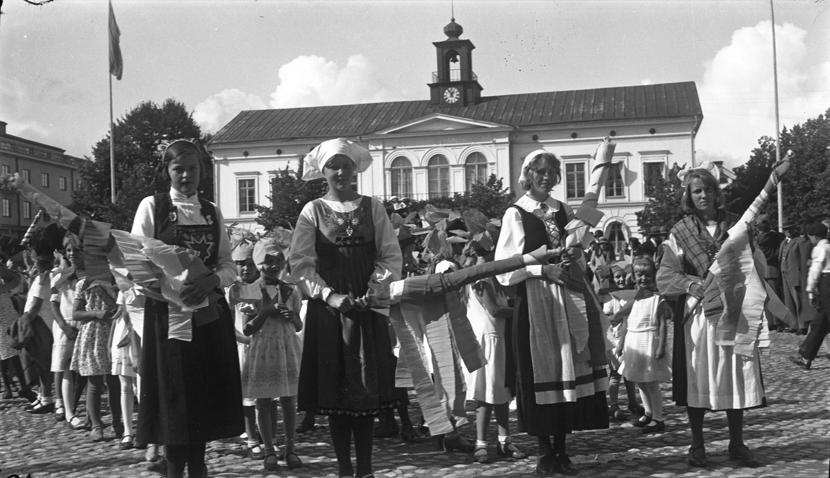 Bild från förberedelserna inför festtåget på söndagen den 4 september 1932 under Barnens dag firandena. Utklädda "marknadsgummor", och bakom dem skolbarn i blomsterdräkt. Fotograf okänd, men liknande bilder var publicerade i Köpingsposten den 5 september 1932.