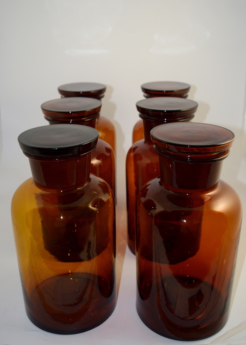 8 stk. brune glasskrukker med vid hals og brune glasspropper. 5000 ml volum, 5 liter. Brukt til oppbevaring av apotekfremstilte tabletter eller pulver ved lagring.