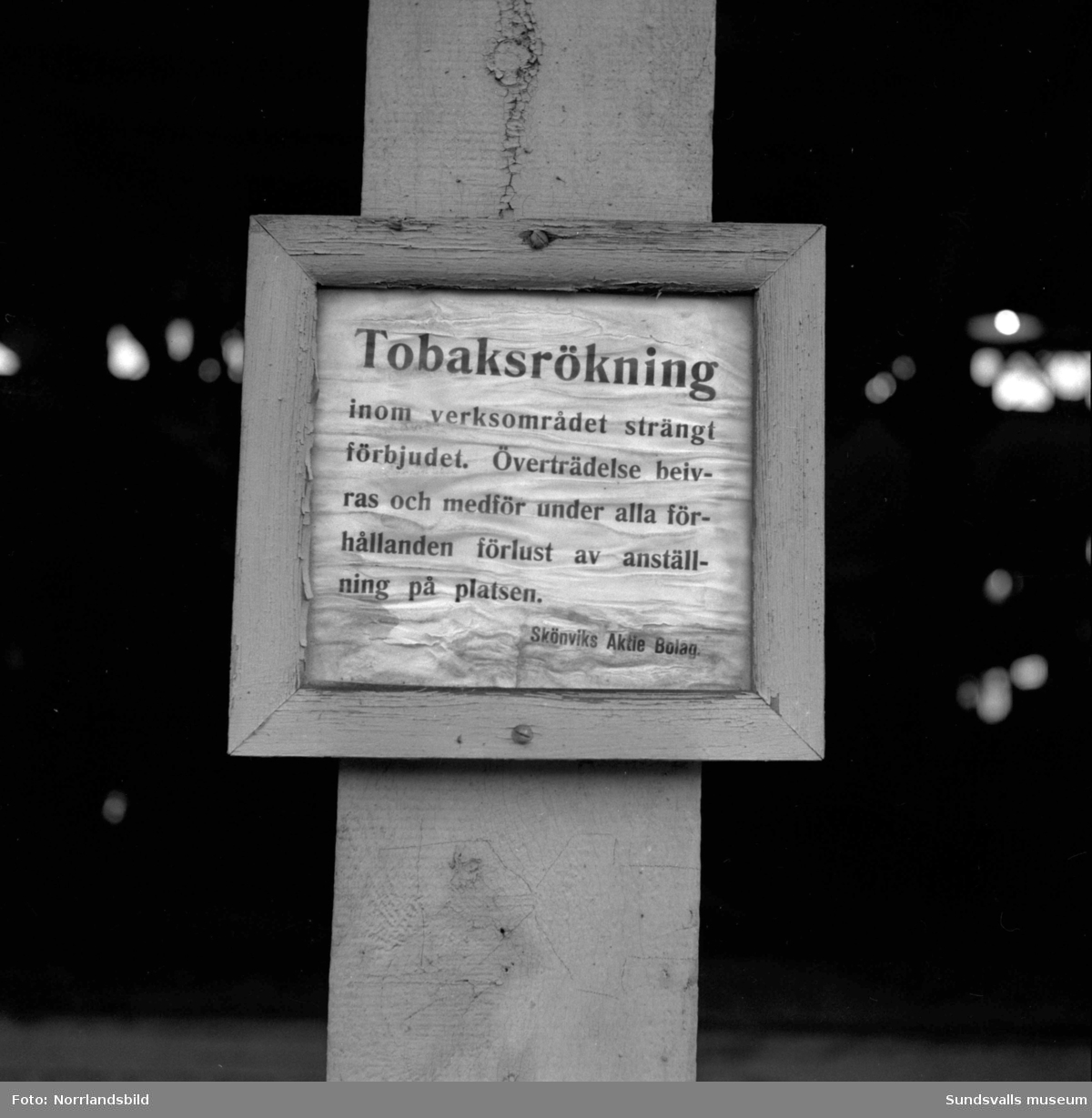 En äldre man som jobbade vid Skönviks sågverk visar upp skyltar om att det är rökning förbjudet på området.
