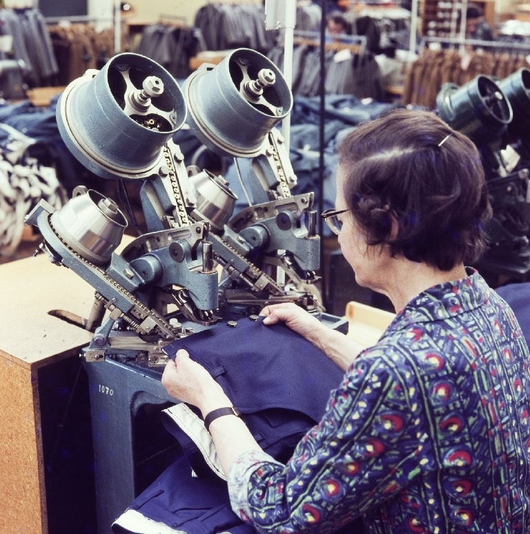Kvinnelig arbeider isette patentknapper på arbeidsklær/jeans med hjelp av en automat i konfeksjonsfabrikken til Jonas Øglænd Sandnes.