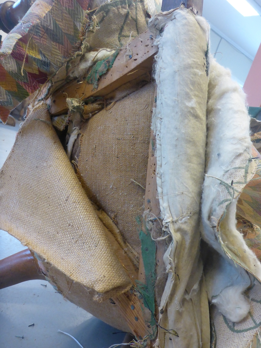 Stolen har en ramme av tre med dreide frambein som er beiset og oljet.