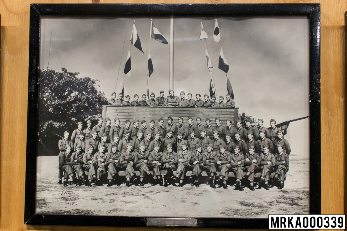 Fotografi taget på befäl och soldater som genomfört grundläggande soldatutbildning på 1:a Batteriet KA 2.
Fotografiet taget på KA 2.
Flobergs Foto 1947.