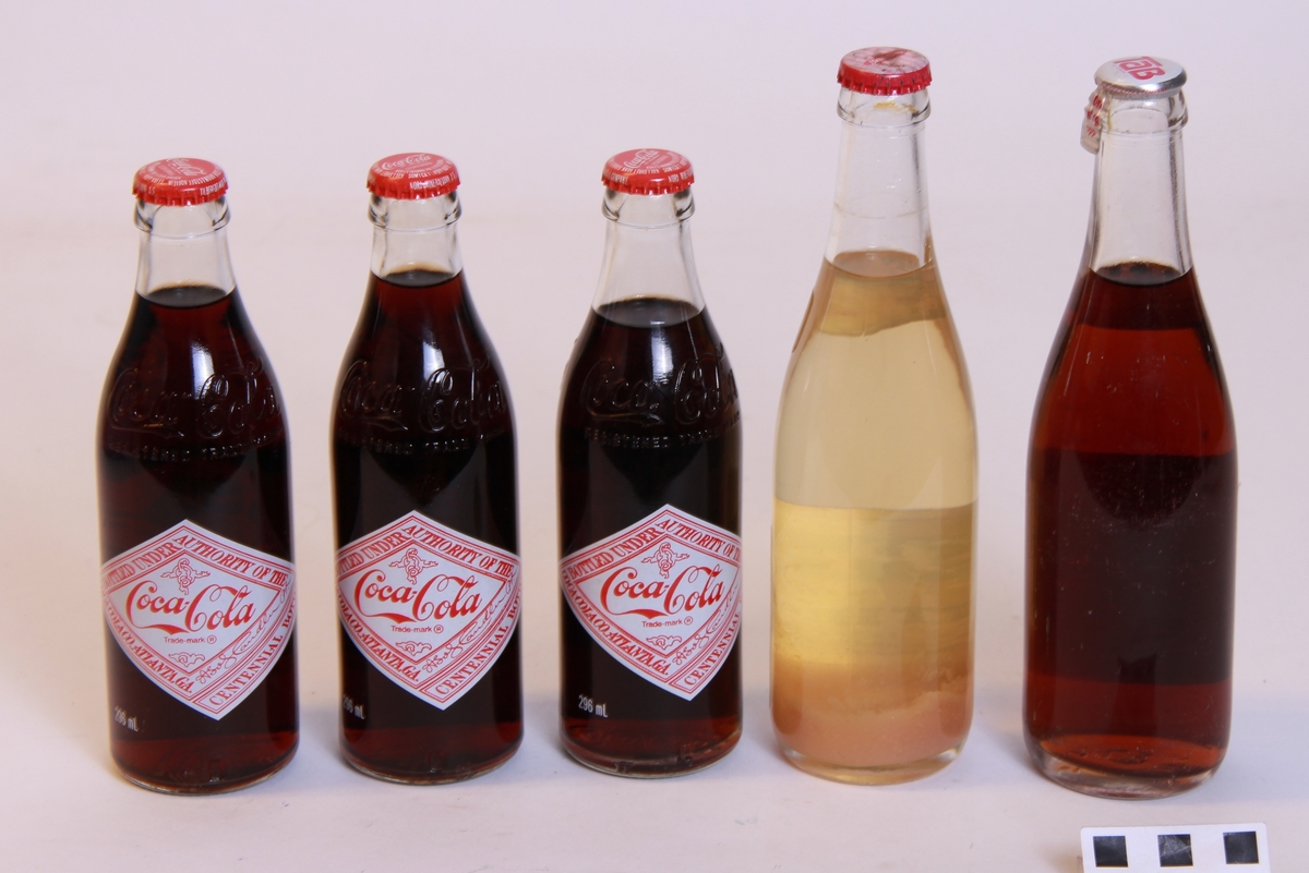 5 uåpna brusflasker.
3 flasker Coca Cola, 100-års jubileumsflasker, 296ml (a)
1 flaske Tab, 350ml (b)
1 flaske Presta Lemon, 350ml (c)

Tab-flaska har rive-flik på korken