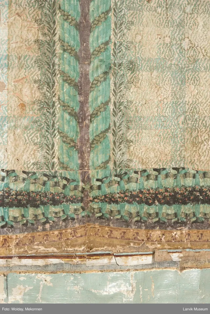 |Tapeten er påmalt tapetborder og brystning. Fra Hovland gård i Larvik.
Den øverste, brede borden: Gerlander/draperi med blomsterranker.
Den nederste, smalere borden: Tekstilbord med blomster. Øver døren til høyre: Stillebenmotiv med blomster og frukt.